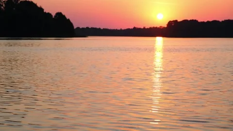 Sunset over a lake with calm water ripples at golden hour. Beautiful landscape Stock Footage 340356527