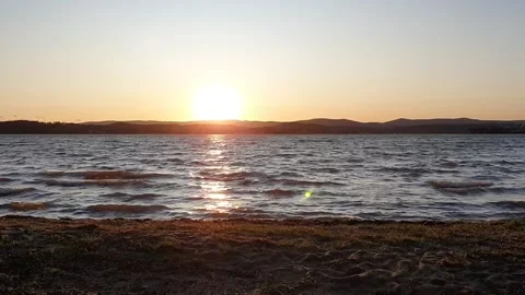 Sunset over the lake, clear sky, windy day, waves rolling on the shore Stock Footage 211065484