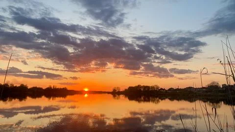 Sunset over lake with clouds reflecting on water and a small town visible a.. Foto stock