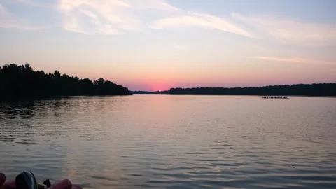 Sunset over a lake with a distant rowboat seen from a motorboat. Tranquil Stock Footage 340356807