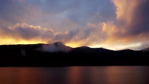 Sunset over a lake in front of mountains Stock Footage 155180284