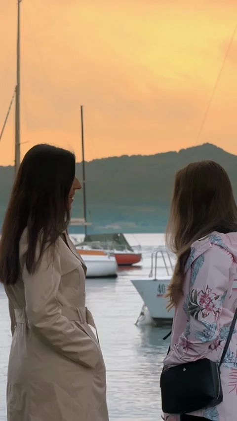 Sunset over the lake, in the mountains. two girls admire the sunset on the lake. Stock Footage 308517530