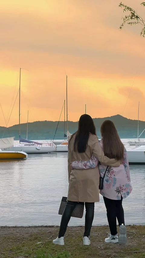 Sunset over the lake, in the mountains. two girls admire the sunset on the lake. Stock Footage 314229164