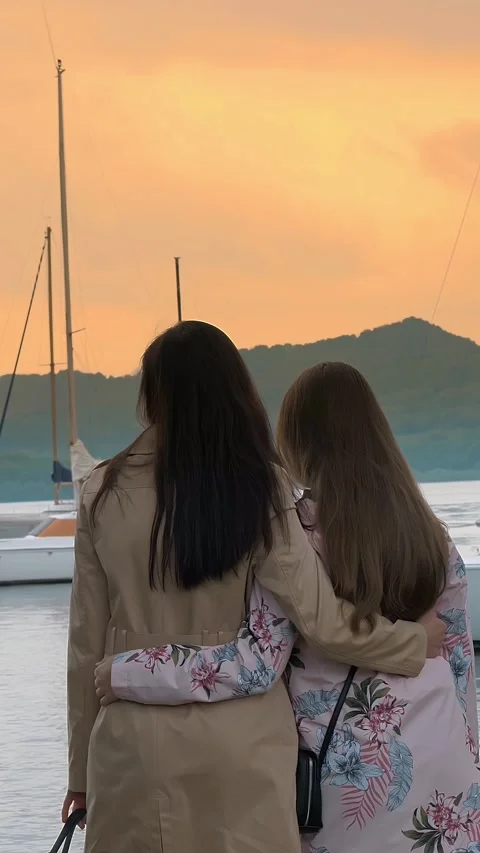 Sunset over the lake, in the mountains. two girls admire the sunset on the lake. Stock Footage 314229347
