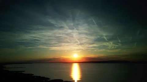 Sunset over lake with plane activity visible on the sky, drone time-lapse 4K Stock Footage 248350187