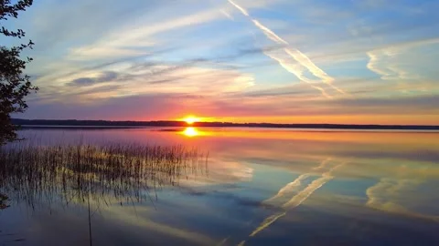 Sunset over the lake with reflections and clouds in the sky 스톡 동영상 340357235