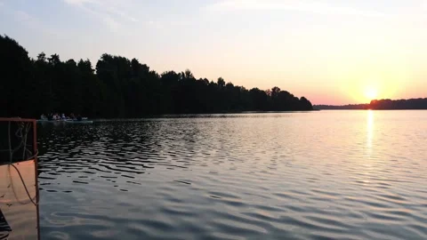 Sunset over lake with silhouettes of rowing boat on water. Golden hour landscape Stock Footage 340356531