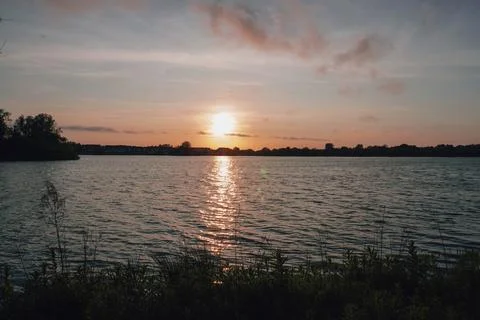 Sunset over a lake with the sun's reflection shimmering on the water Stock Photos