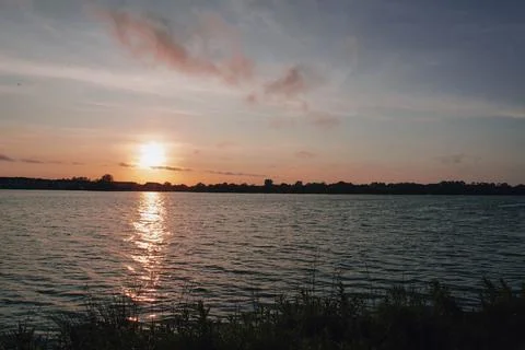 Sunset over a lake with the sun's reflection shimmering on the water Stock Photos
