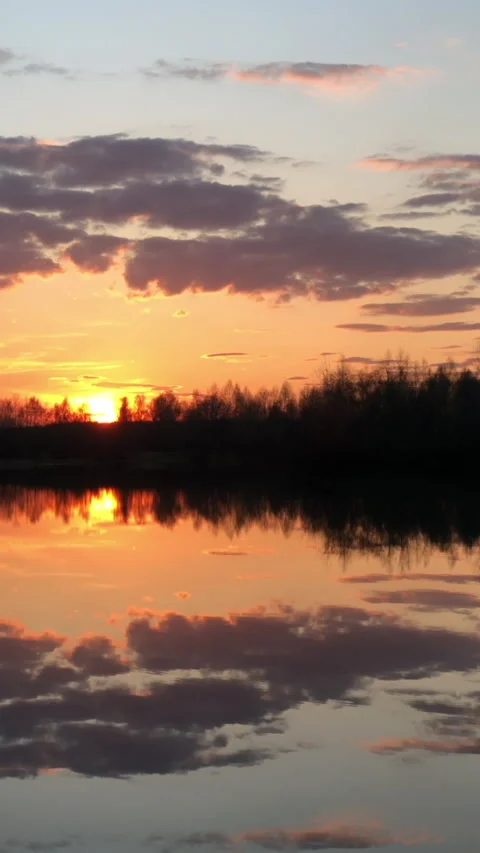 Sunset over lake. Trees silhouetted on horizon.  Vertical format Stock Footage 153267973