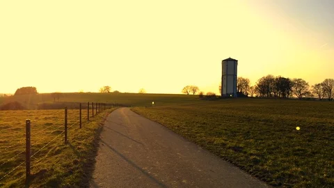 Sunset over the long path and water tower Stockbeeldmateriaal 87646175