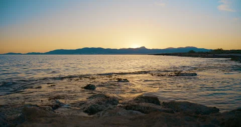 Sunset Over Mallorca Mountains with Gentle Waves on Rocky Shore Stock Footage 343589523