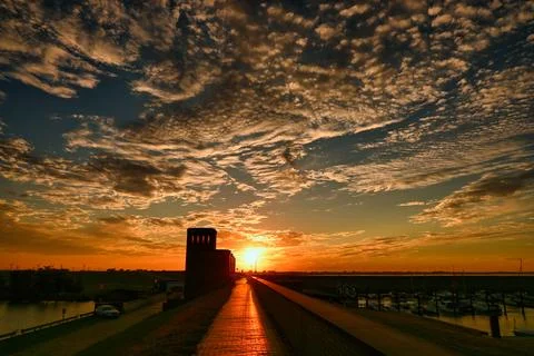 Sunset over the marina with clouds and silhouettes of structures Stock Photos