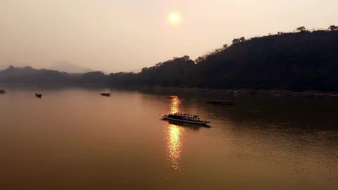 Sunset Over the Mekong River with Traditional Longboats and Mountain Landscape Stock Footage 342334767
