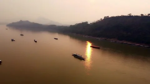 Sunset Over the Mekong River with Traditional Longboats and Mountain Landscape Stock Footage 342334772