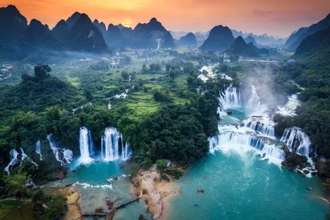 Sunset over mountain range with Ban Gioc waterfall flowing in tropical rain.. Foto stock