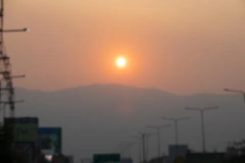 A sunset over a mountain range with a few street lights in the background Stock Photos