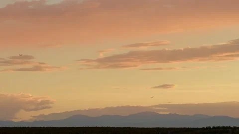 Sunset over Mountain Range with Plane Flying through Frame Stock Footage 168759801