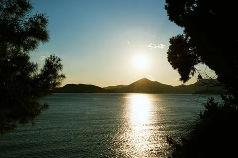Sunset over a mountain range by the sea, view from the forest Stock Photos
