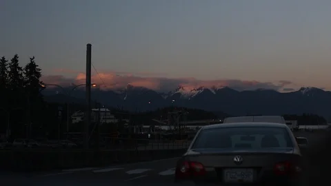 Sunset Over Mountains In The Distance While Waiting In Traffic For Ferry At Dusk Stock Footage 99940213