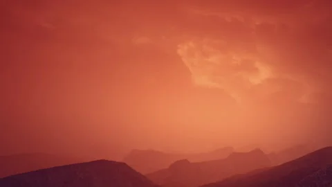 Sunset over mountains with orange sky and clouds in the distance Stock Footage 340230956