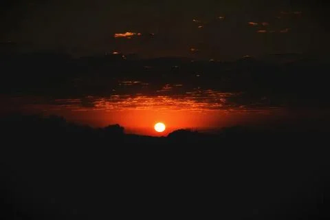Sunset over mountains with orange sky and clouds Stock Photos