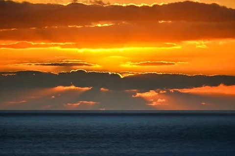 Sunset over the ocean with clouds and golden rays shining through in the ev.. Stock Photos