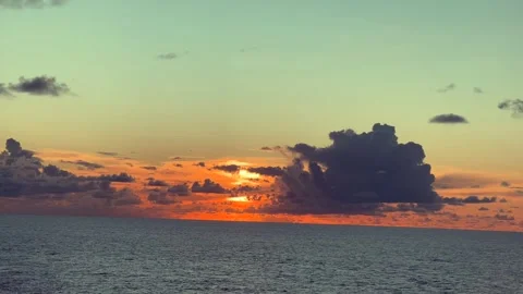 Sunset over the ocean with clouds creating a vibrant orange and blue sky Stock Footage 338282589