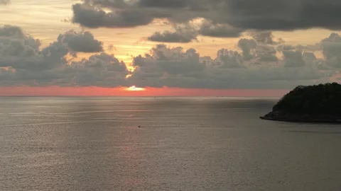 Sunset over ocean with clouds reflecting warm colors near coastal landscape Vídeos de archivo 342332135