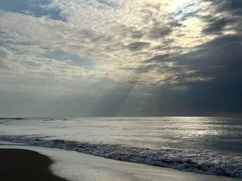 Sunset over the ocean with cloudy sky and gentle waves Stock Photos