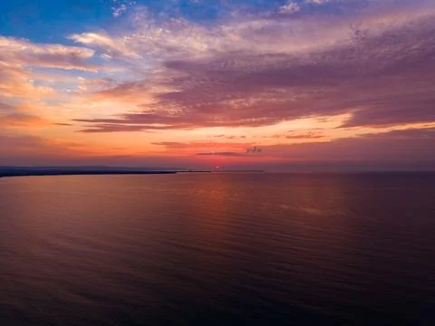 Sunset over the ocean with colorful clouds and calm water near the coast at.. Stockfoto's