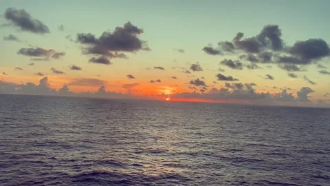 Sunset Over Ocean with Colorful Sky and Clouds Reflecting on Calm Water Stock Footage 338280046