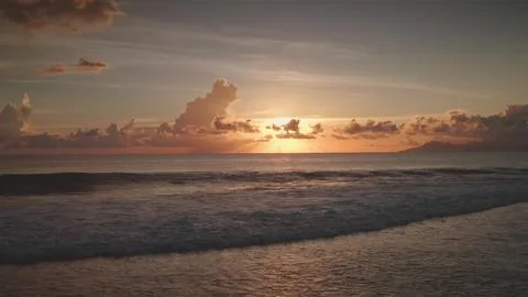 Sunset over the ocean creating golden reflections on waves in Tahiti Stock-Fotos