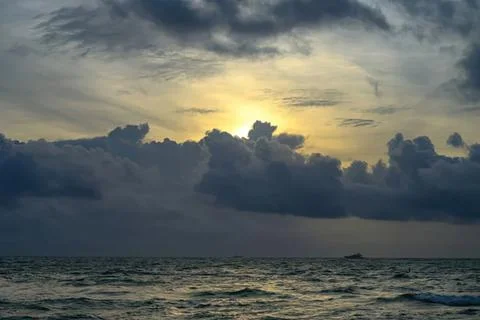 Sunset over ocean with dark clouds and calm waves Stock Photos