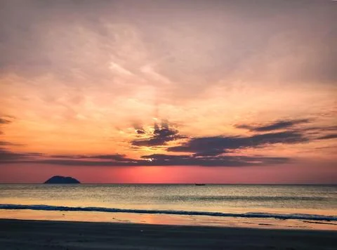 Sunset over the ocean with dark clouds and light rays at a beach with shall.. Stock Photos