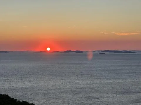 Sunset over the ocean with distant islands visible on the horizon during the Stock Photos