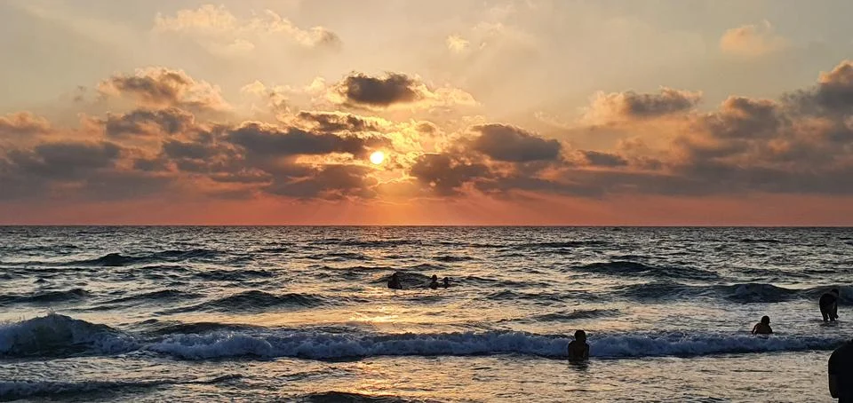Sunset over the ocean with dramatic clouds and golden rays reflecting on the Stock Photos