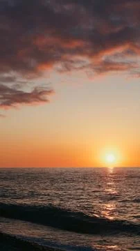 Sunset over ocean horizon with waves and colorful sky at dusk Stock Photos