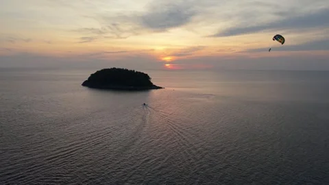 Sunset over ocean with island and parasailing activity in the distance 動画素材 336926628