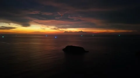 Sunset over ocean with island silhouette and distant lights on water Stock-Footage 342332813