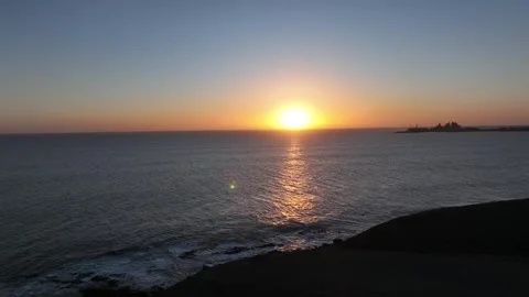 Sunset Over Ocean as Large Wave Rolls In Near Distant Pier Stock Footage 309940465