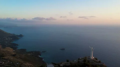 Sunset Over the Ocean With a Lighthouse and a Ship Near a Coastal Mountain Stock Footage 322934505