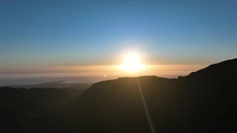 Sunset Over Ocean with Mountain Silhouettes in Foreground Stock Footage 309945759