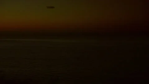 A sunset over the ocean with a plane and hot air balloon in the sky Stock Footage 317955386