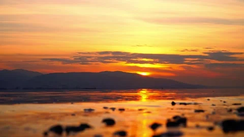A sunset over the ocean with a rock in the water Stock Footage 331257682
