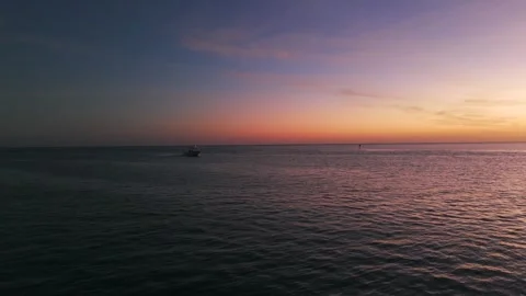 Sunset over ocean with sky transitioning from blue to warm hues of orange and Stock Footage 264521869