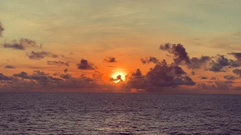 Sunset over the ocean with vibrant clouds and calm waves under a colorful sky Stock Footage 338282512
