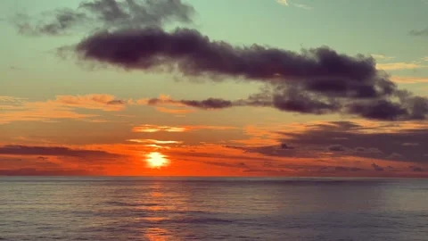 Sunset over the ocean with vibrant orange and red hues and dramatic clouds .. Stock Footage 338281944