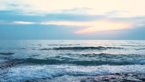 Sunset over the ocean viewed from a rcoky beach, capturing vibrant colors Stock Footage 297310526
