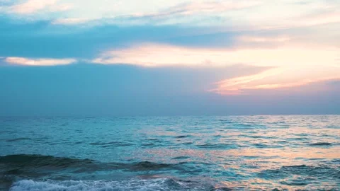 Sunset over the ocean viewed from a rocky beach during blue hour Stock Footage 297310055